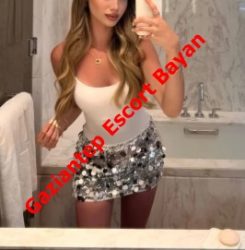 Mirror selfie of a woman in a white tank top and silver sequin mini skirt in a bathroom, with red diagonal text 'Gaziantep Escort Bayan' across her torso.