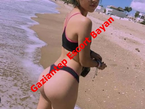 Woman in a black and pink bikini on a sandy beach by the water, with red diagonal text 'Gaziantep Escort Bayan' across the image.